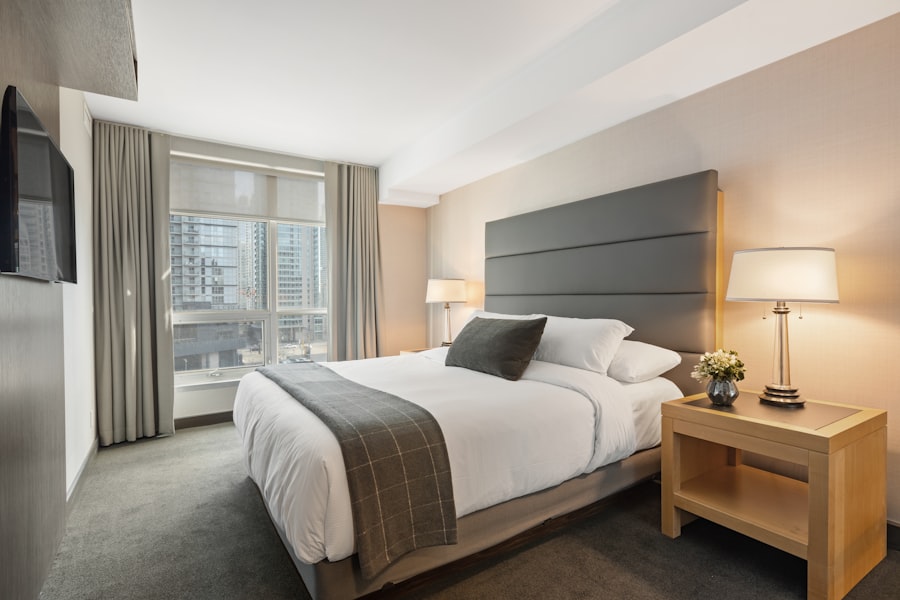 A bright hotel bedroom with white linen and a window overlooking the city