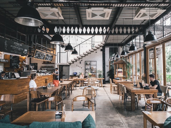 A restaurant dining room with wooden tables and large windows